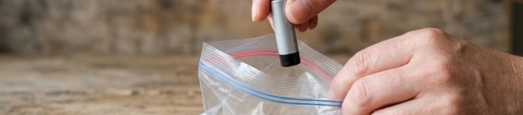 Hand placing a single battery into a small clear plastic bag